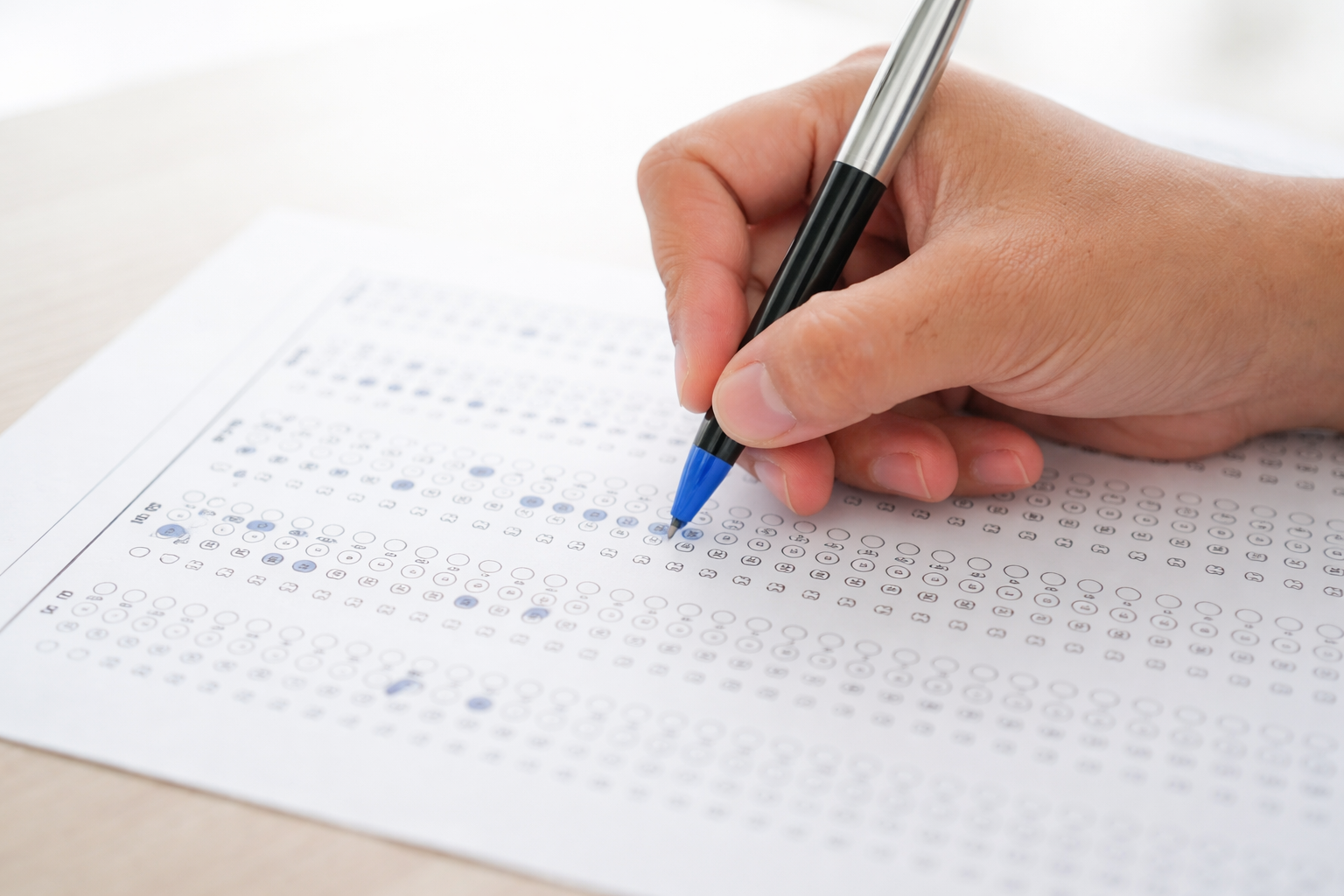 Provas do concurso IBGE são neste domingo, 01/03 – Veja horários, documentos e orientações! 2 Pessoa preenchendo gabarito de múltipla escolha com caneta azu
