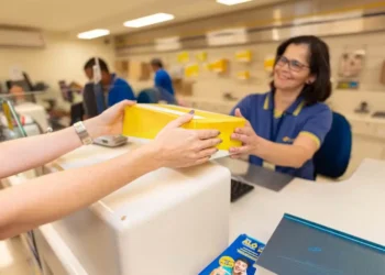 Funcionária dos Correios entregando um pacote a um cliente, com destaque para o serviço postal.