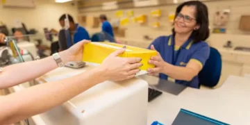 Funcionária dos Correios entregando um pacote a um cliente, com destaque para o serviço postal.