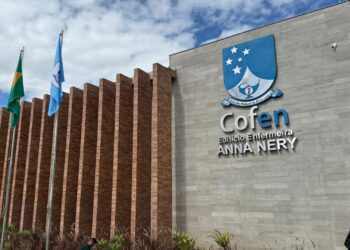 Fachada do edifício Anna Nery do Cofen com bandeiras e céu parcialmente nublado