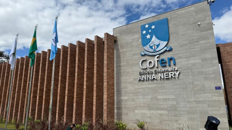Salários de quase R$ 19 mil! Concurso do Cofen terá edital entre março e abril 1 Fachada do edifício Anna Nery do Cofen com bandeiras e céu parcialmente nublado