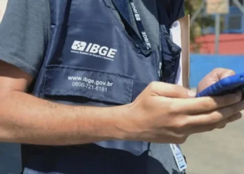 Agente do IBGE utilizando celular durante coleta de dados em campo, ilustrando expectativa para o novo concurso do instituto com 39 mil vagas previstas.