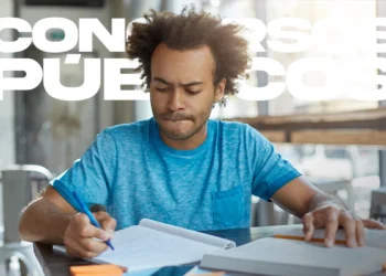 Homem jovem com cabelo afro, vestindo t-shirt azul, concentrado a escrever num caderno sobre uma mesa de madeira. À frente dele, um documento impresso com o título "EDITAL MP-ES". Sobreposta à imagem, a frase em letras grandes: "CONCURSO MP-ES LANÇADO 60 VAGAS".