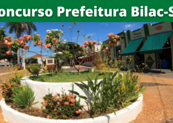 Jardim com flores e árvores ao centro de praça próxima a comércios em Bilac-SP, sob faixa do concurso