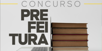 Pilha de livros encostada em um notebook aberto sobre superfície clara