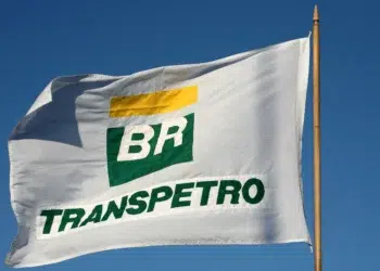 Bandeira branca da Transpetro tremula ao vento sob céu azul durante preparação para concurso