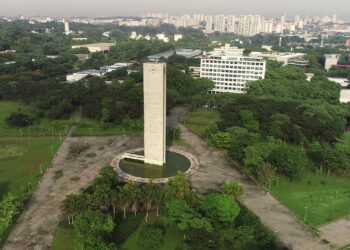 Vista aérea do Relógio da USP cercado por áreas verdes e prédios no campus