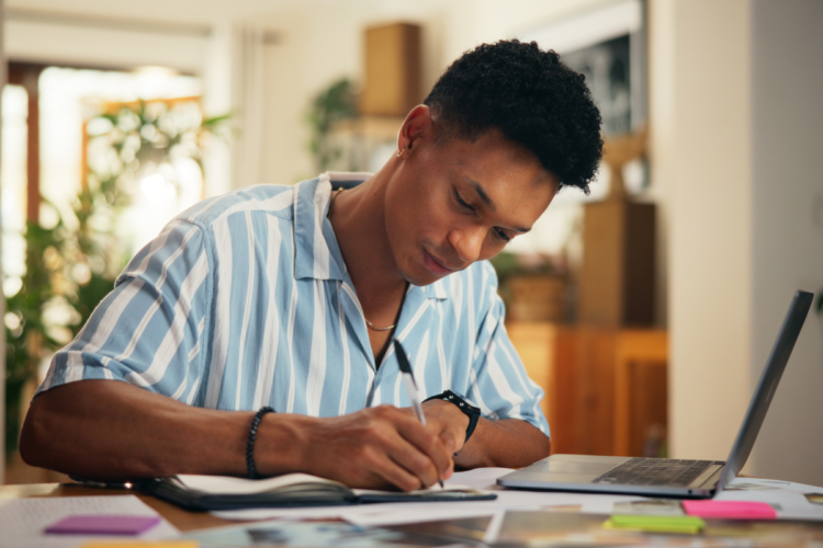 Como estudar para concursos públicos como os aprovados de verdade estudam 1 Homem escreve em caderno ao lado de notebook em mesa com papéis coloridos