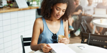 Mulher estudando disciplinas essenciais para concursos públicos em café