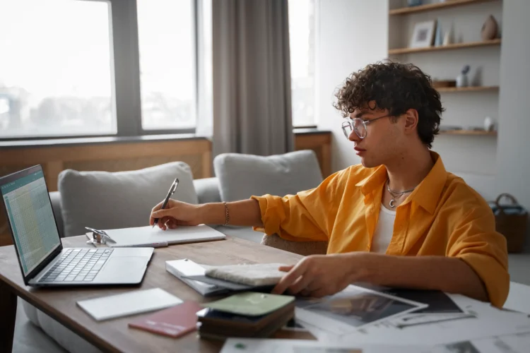 Pessoa estudando para concurso em casa, com laptop e material de apoio sobre a mesa, em ambiente tranquilo.