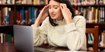Estudante revisando conteúdo no notebook com expressão de dificuldade de memorização durante preparação para concurso público.