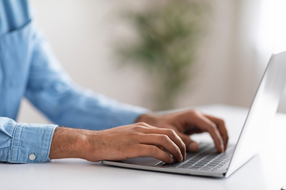 Saiu o edital do concurso CGE AL com vagas de analista; salários de R$ 6,8 mil 2 Pessoa com camisa azul digita em notebook sobre mesa branca