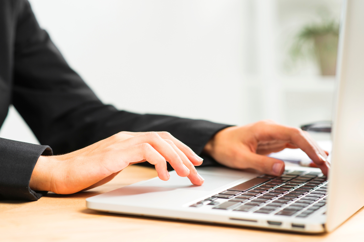 SAIU EDITAL! Novo concurso oferece vagas para Farmacêutico, Eletricista, Agente Comunitário de Saúde e outros cargos - Salários de até R$ 10,6 mil 2 Pessoa com terno preto digitando em notebook sobre mesa de madeira clara