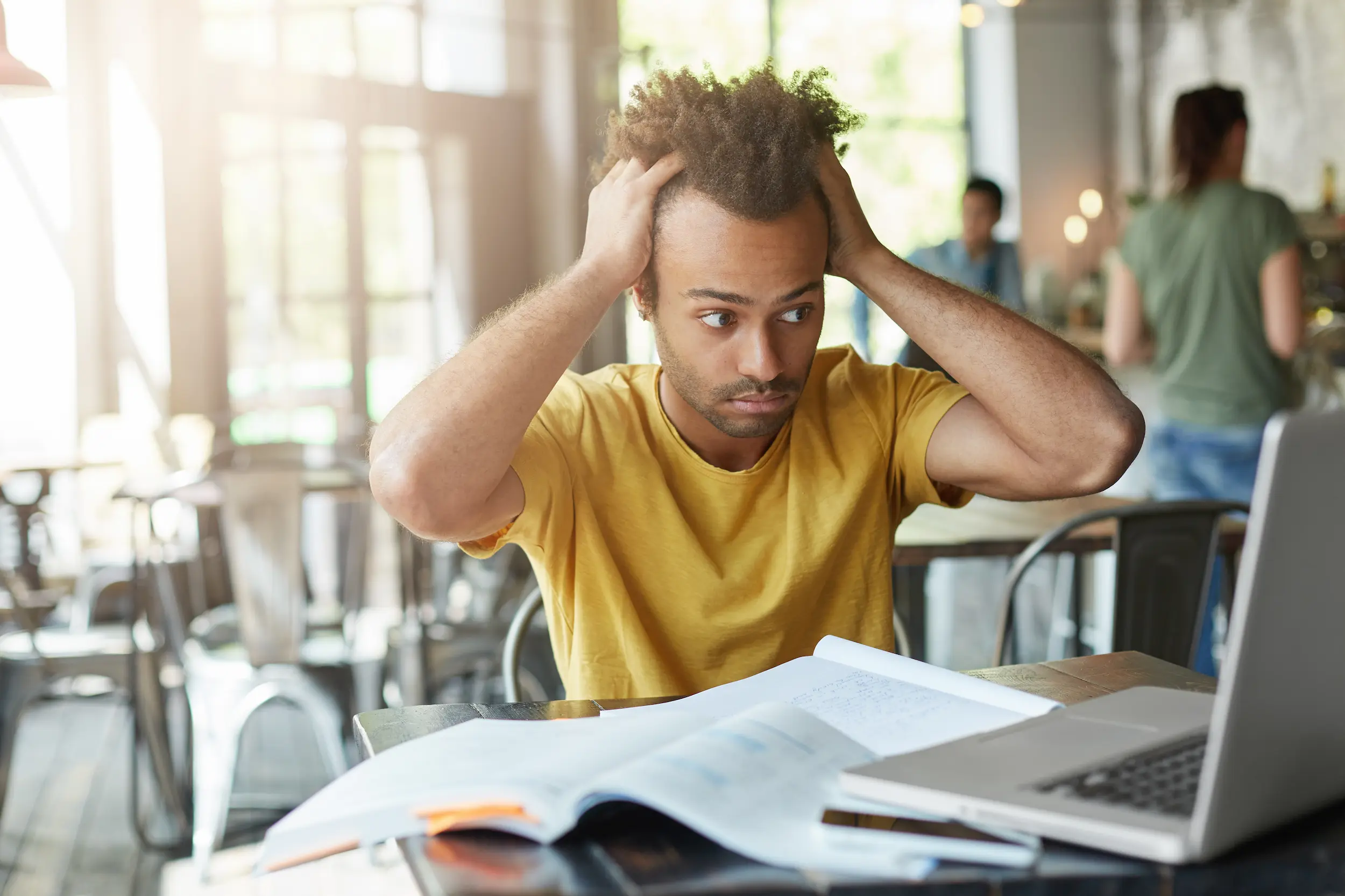Estuda e esquece tudo? Essas estratégias vão mudar seu desempenho nos estudos para concursos 2 Estudante com dificuldade para lembrar conteúdo enquanto revisa material para concurso em frente ao notebook.
