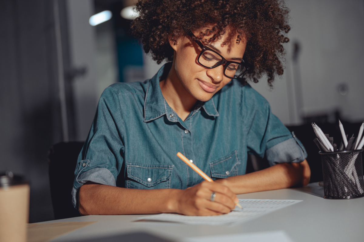 Como estudar para concursos públicos como os aprovados de verdade estudam 2 Mulher de óculos escreve concentrada em folha sobre mesa iluminada