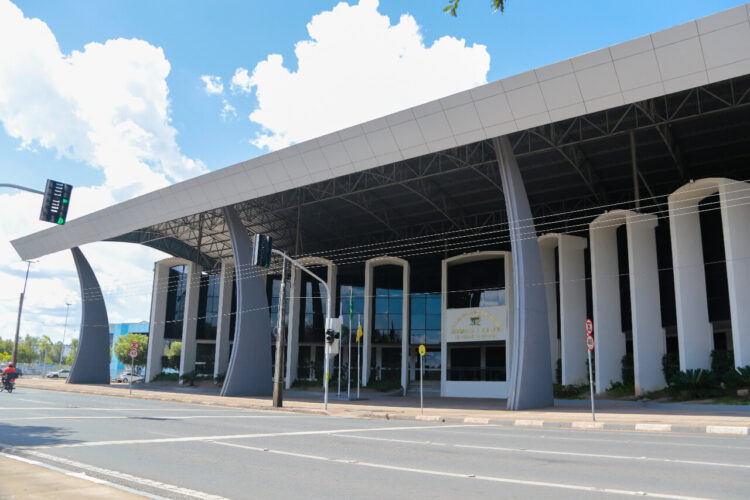 Assembleia Legislativa de Roraima abre concursos com salários de até R$ 39,5 mil 1 Fachada do Palácio Antonio Martins em Boa Vista, com pilares arqueados em concreto, cobertura metálica e brasão da ALE-RR.
