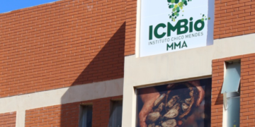 Prédio de tijolos do ICMBio com logotipo verde em forma de mapa do Brasil e painel exibindo mãos com castanhas