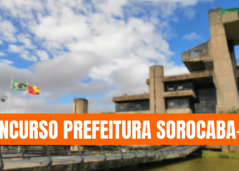 Prédio moderno, três bandeiras hasteadas, faixa laranja com texto sobre concurso público