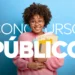 Mulher jovem de óculos, cabelo cacheado, segurando pastas coloridas, sorrindo em frente a fundo azul com texto “CONCURSO PÚBLICO”