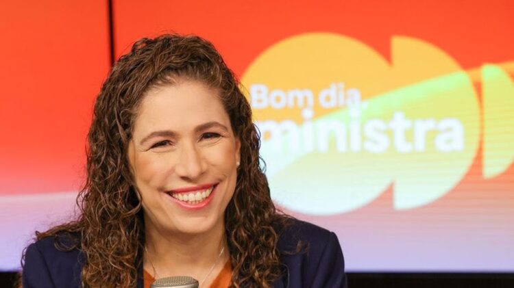 Concurso PF: ministra Esther Dweck confirma convocação de 1.500 excedentes 2 Esther Dweck sorrindo em estúdio com fundo laranja e logo do Bom Dia Ministra