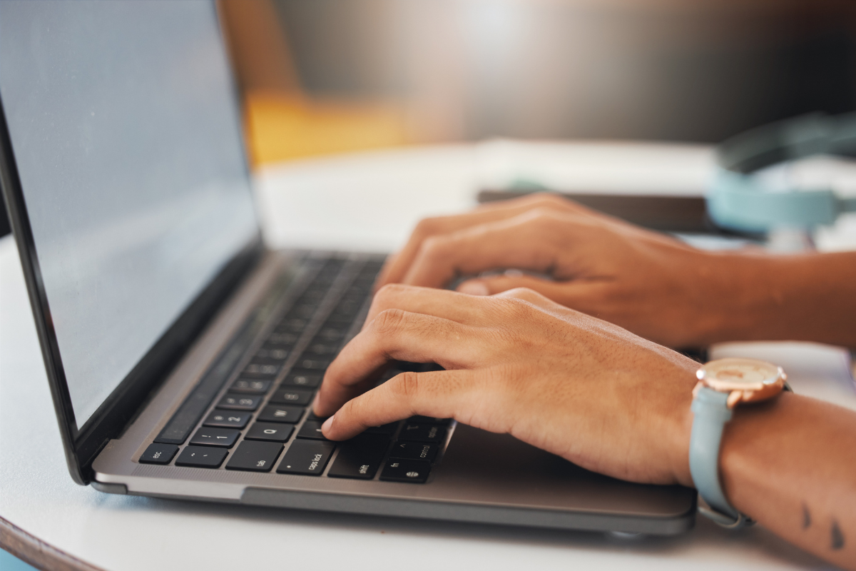 Processo Seletivo em Júlio Mesquita - SP encerra inscrições nesta segunda (13); veja as vagas disponíveis 2 Mãos femininas digitando em teclado de laptop cinza, usando relógio dourado com pulseira azul-turquesa