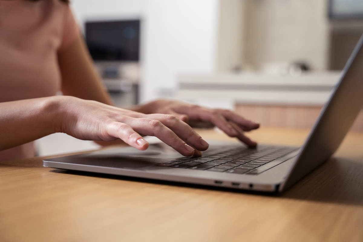 Concurso em Sorocaba-SP: últimas horas para se inscrever nas 26 vagas na área da saúde 2 Mãos de uma pessoa digitando em um notebook sobre mesa de madeira em ambiente de cozinha